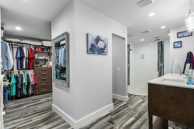 walk in closet featuring visible vents, wood finished floors, and a sink