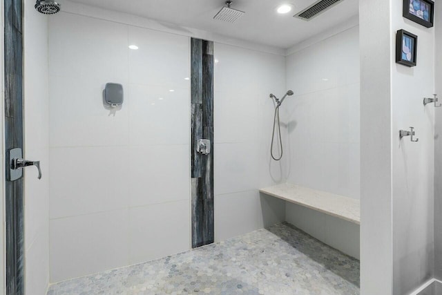 bathroom with tiled shower and visible vents