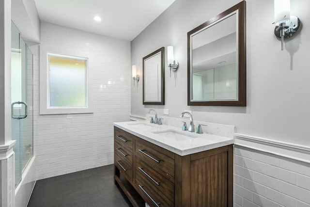 full bath featuring a sink, wainscoting, double vanity, and tile walls