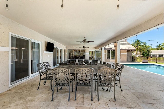 view of patio featuring ceiling fan, outdoor dining area, fence, and a fenced in pool
