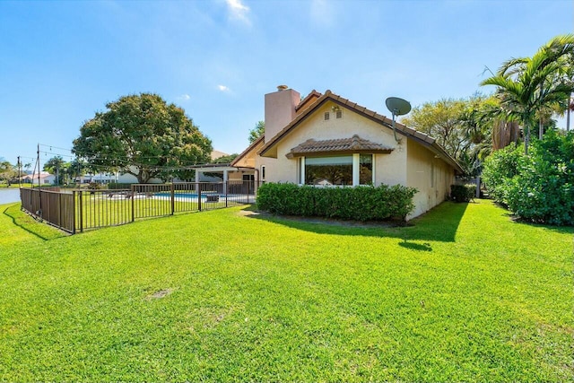 back of property featuring stucco siding, fence, a fenced in pool, a yard, and a chimney