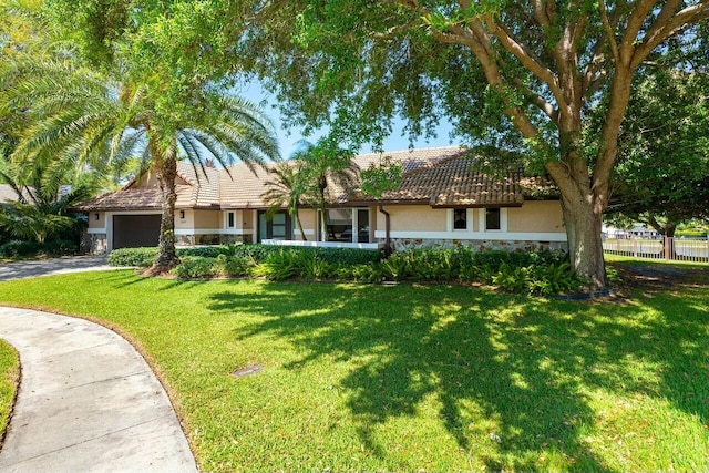 single story home featuring stucco siding, an attached garage, stone siding, driveway, and a front lawn