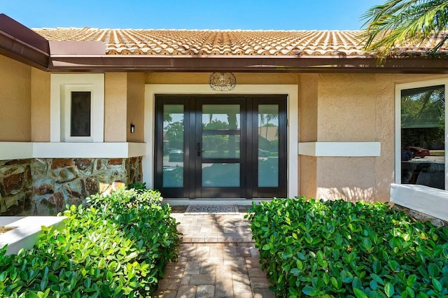 doorway to property featuring stucco siding, a tiled roof, and french doors