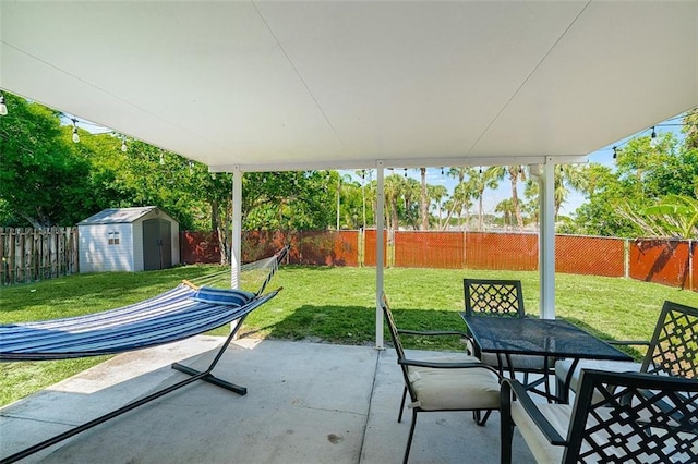 view of patio featuring a fenced backyard, a storage unit, outdoor dining area, and an outdoor structure