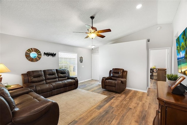 living area with a textured ceiling, wood finished floors, baseboards, ceiling fan, and vaulted ceiling