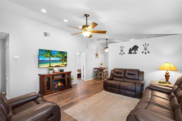 living area featuring visible vents, a textured ceiling, ceiling fan, and wood finished floors