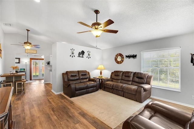 living area featuring lofted ceiling, wood finished floors, a ceiling fan, and visible vents