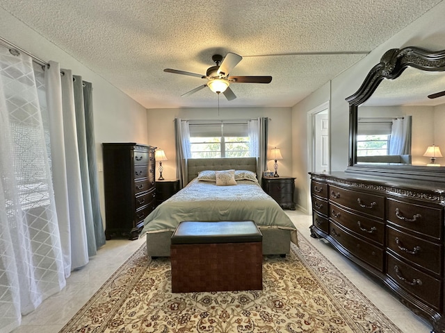 bedroom with light tile patterned floors, multiple windows, a textured ceiling, and a ceiling fan