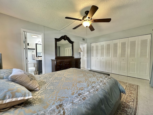 tiled bedroom featuring visible vents, a textured ceiling, ensuite bath, a closet, and ceiling fan