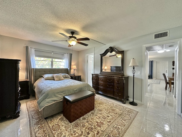 bedroom with baseboards, a ceiling fan, visible vents, and a textured ceiling