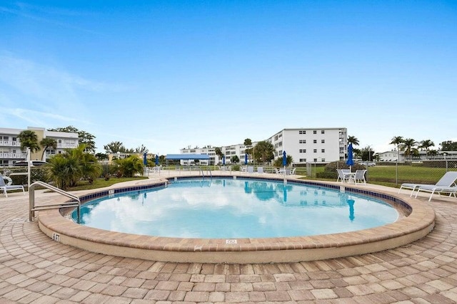 community pool with a patio area and fence