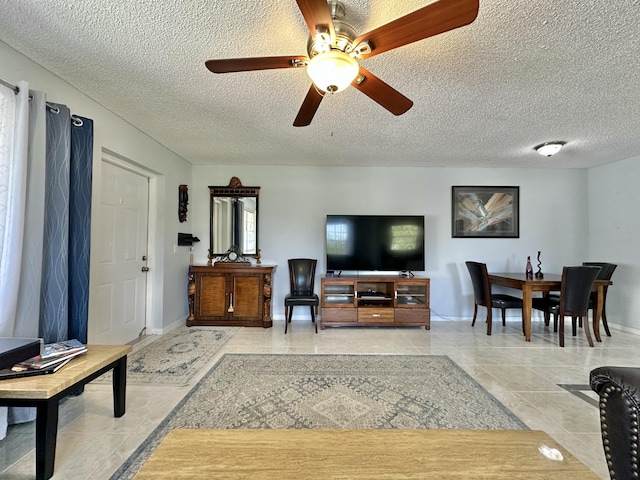 living room with light tile patterned floors, baseboards, a textured ceiling, and a ceiling fan