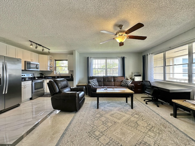 living area with a textured ceiling, marble finish floor, and a ceiling fan