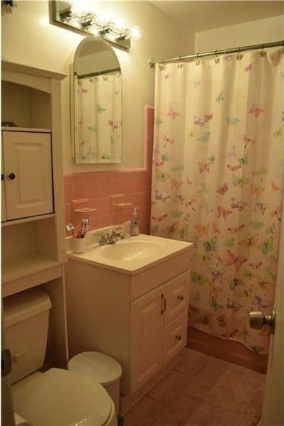 bathroom featuring vanity, a shower with curtain, a wainscoted wall, tile walls, and toilet