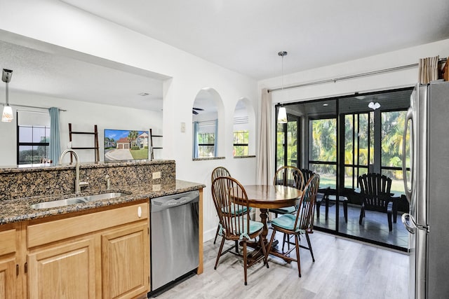 kitchen featuring a sink, stainless steel appliances, plenty of natural light, and dark stone counters