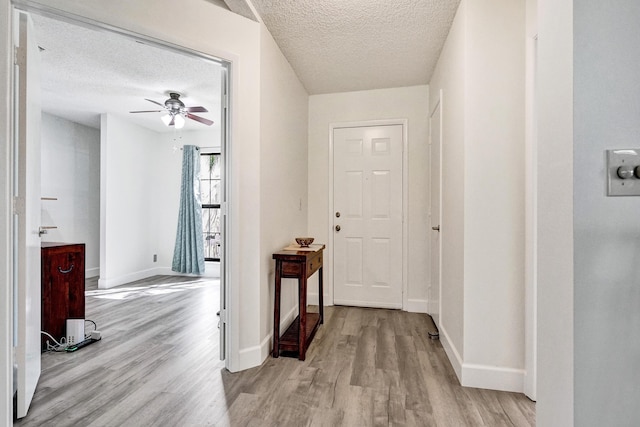 hallway featuring wood finished floors, baseboards, and a textured ceiling