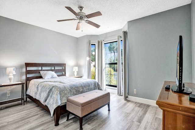 bedroom with light wood-style flooring, a textured ceiling, baseboards, and ceiling fan