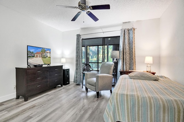 bedroom featuring baseboards, light wood-style floors, a ceiling fan, and a textured ceiling