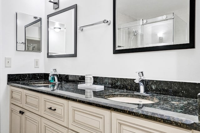 bathroom with double vanity, walk in shower, and a sink