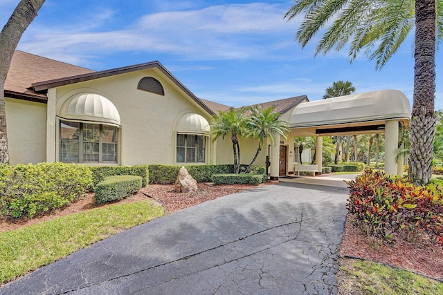 view of front facade with an attached carport, driveway, and stucco siding