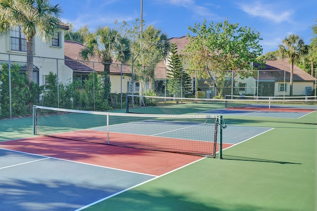 view of tennis court featuring community basketball court and fence