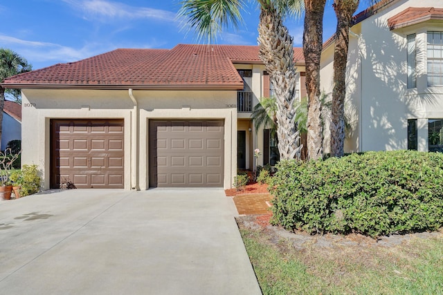 mediterranean / spanish-style house with a tiled roof, a garage, driveway, and stucco siding