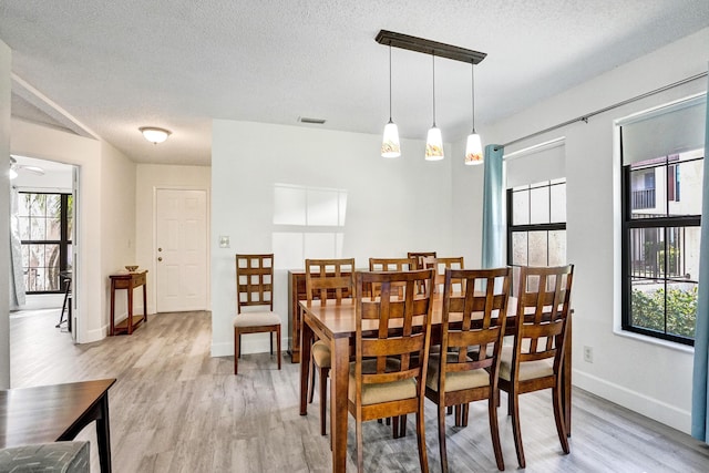 dining space featuring visible vents, a textured ceiling, light wood-type flooring, and baseboards