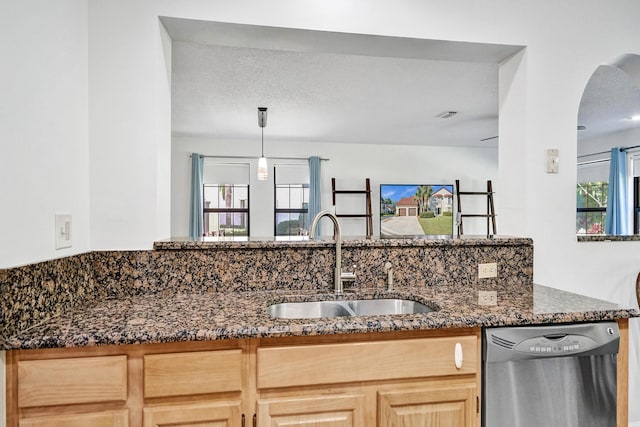 kitchen with dishwasher, dark stone countertops, plenty of natural light, and a sink