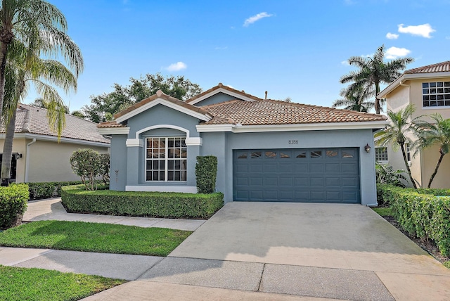 view of front of house with a tile roof, concrete driveway, stucco siding, and an attached garage