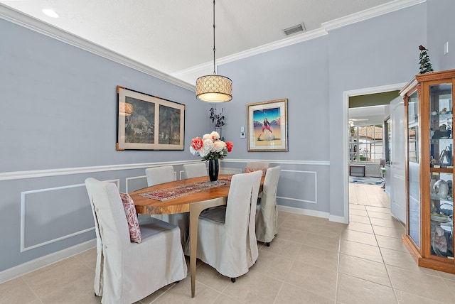 dining space with a wainscoted wall, a decorative wall, light tile patterned floors, visible vents, and ornamental molding