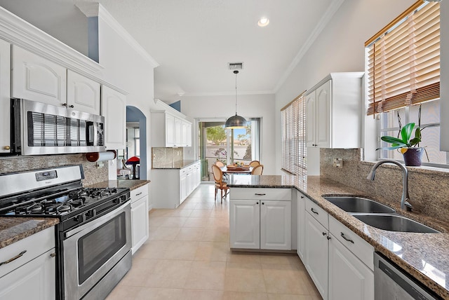 kitchen featuring a sink, a peninsula, stainless steel appliances, white cabinets, and ornamental molding