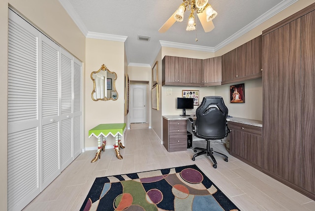 office area featuring built in desk, crown molding, ceiling fan, and visible vents