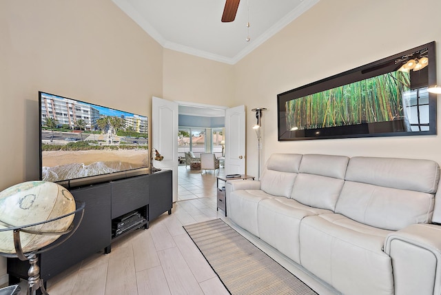 living area featuring ceiling fan, a high ceiling, light wood-style floors, and ornamental molding
