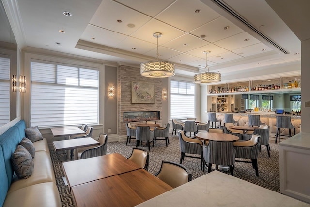carpeted dining area with a community bar, a raised ceiling, crown molding, and a fireplace
