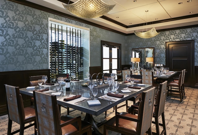 dining space with a wainscoted wall, ornamental molding, and wallpapered walls