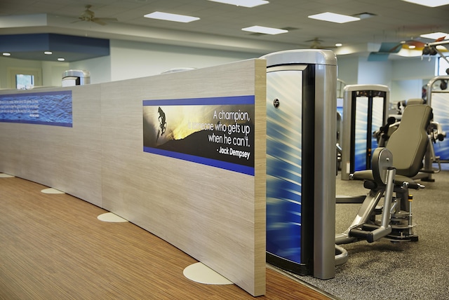 gym featuring a drop ceiling and a ceiling fan
