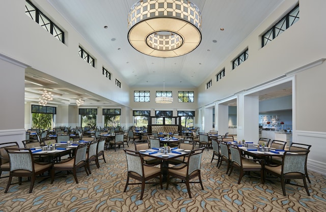 carpeted dining area with high vaulted ceiling