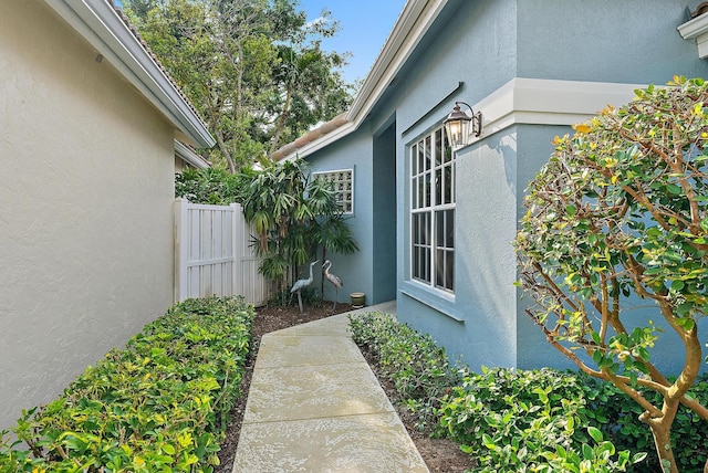 view of property exterior with stucco siding and fence