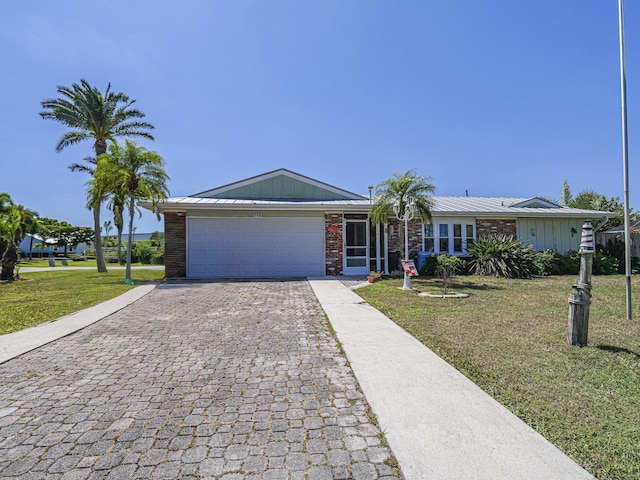 view of front of property with brick siding, a front yard, decorative driveway, and a garage