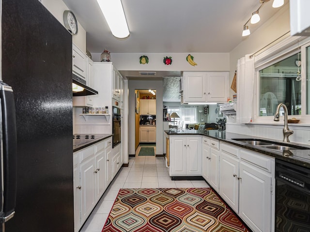 kitchen with a sink, black appliances, light tile patterned flooring, and white cabinets