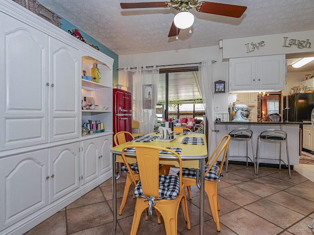 dining room featuring a textured ceiling, light tile patterned floors, and ceiling fan