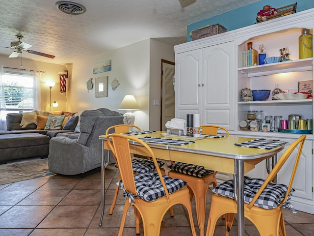 tiled dining area with visible vents, a textured ceiling, and a ceiling fan