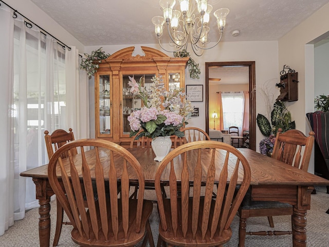 dining room featuring light colored carpet, a chandelier, and a textured ceiling