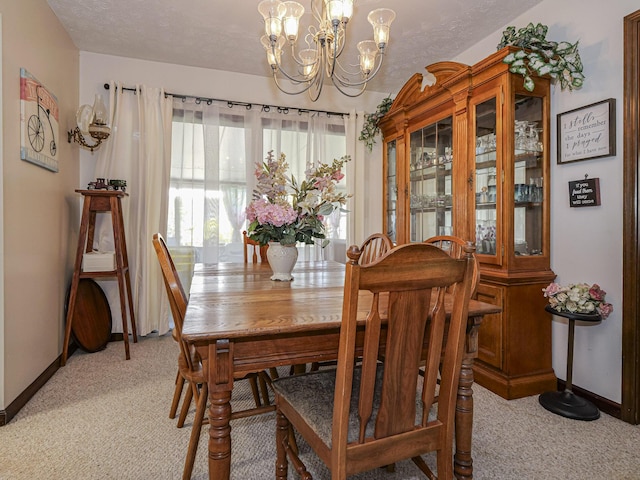 dining space featuring a chandelier, light colored carpet, a textured ceiling, and baseboards