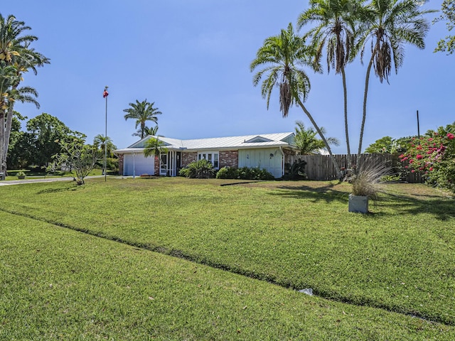 view of front facade with metal roof, a front lawn, and fence