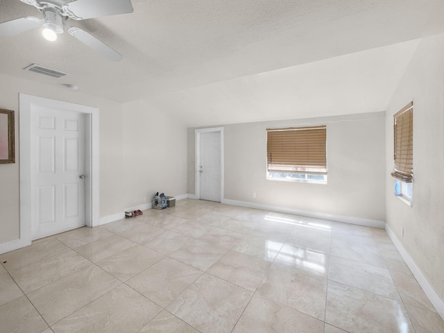 unfurnished room featuring a textured ceiling, ceiling fan, vaulted ceiling, and baseboards