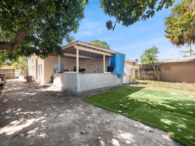 back of house featuring fence, central AC unit, a lawn, and stucco siding