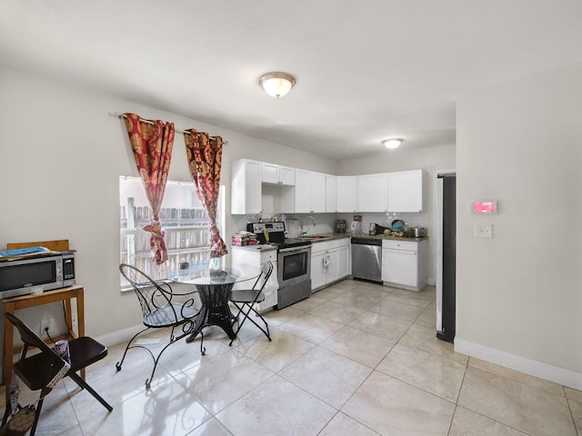 kitchen featuring a sink, light tile patterned floors, baseboards, white cabinets, and appliances with stainless steel finishes