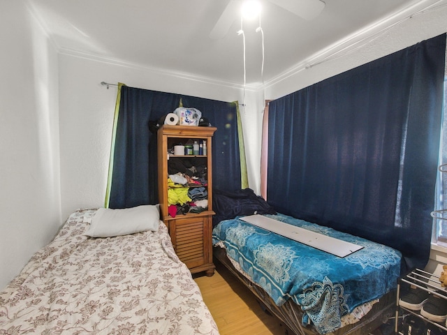 bedroom featuring wood finished floors, ceiling fan, and ornamental molding