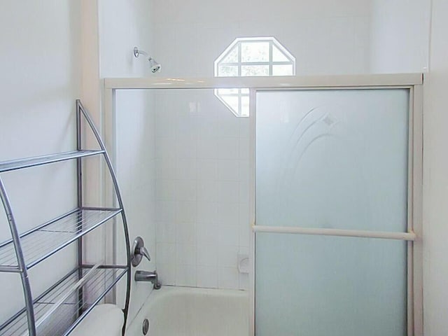 bathroom featuring combined bath / shower with glass door and toilet